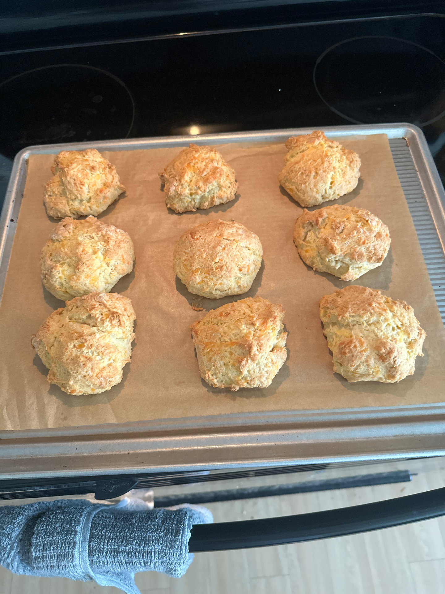 A tray of fresh cheddar drop biscuits cooling on the stove